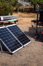 Vor einem Wohnwagen steht eine mobile Powerstation mit einem Solarpanel.