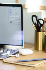 Neben einem MacBook Pro liegen AirPods und das dazugehörige Case.