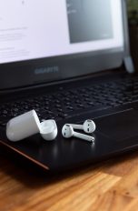 AirPods und das dazugehörige Case liegen auf einem Windows-Laptop.