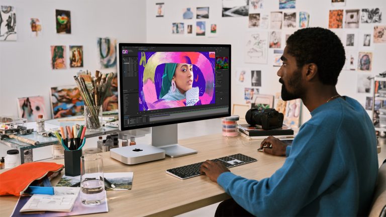 Eine Person sitzt vor einem Mac mini und bearbeitet ein Bild.