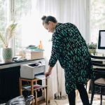 Eine Person steht vor einem Drucker und nimmt einen Ausdruck heraus.