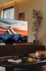 Blick in ein Wohnzimmer, in dem ein Samsung-Fernseher steht, auf den ein Hund schaut.