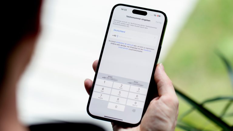 Eine Person hält ein Smartphone in der Hand, auf dem der Einrichtungsprozess von WhatsApp zu sehen ist.