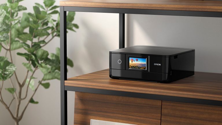 Ein Epson Expression Photo XP-8700 steht in einem Regal und zeigt ein Bild auf dem Display an.