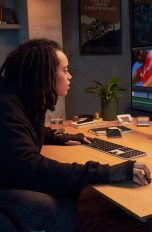 Eine Person sitzt an einem Schreibtisch vor einem Apple Studio Display.