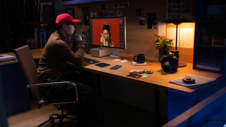 Eine Person sitzt an einem Schreibtisch, auf dem ein Apple Studio Display steht. Eine Person sitzt an einem Schreibtisch, auf dem ein Apple Studio Display steht.