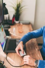 Eine Person steckt eine externe Festplatte an einen Laptop an.