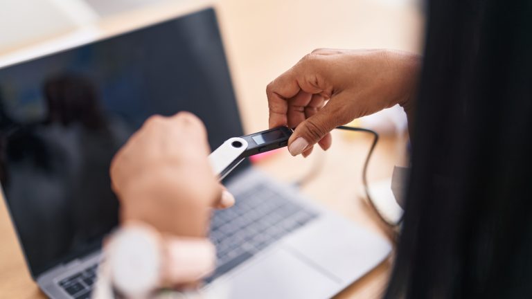 Eine Person steckt einen USB-Stick an einen Laptop an. Eine Person steckt einen USB-Stick an einen Laptop an.