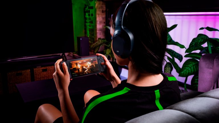 Eine Person sitzt auf einem Sofa und spielt auf einem Smartphone, das in einen Razer-Kishi-Controller eingesteckt ist.