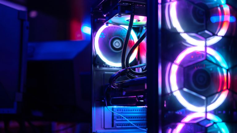 Blick in ein PC-Gehäuse, in dem mehrere bunt erleuchtete Lüfter rotieren. Blick in ein PC-Gehäuse, in dem mehrere bunt erleuchtete Lüfter rotieren.
