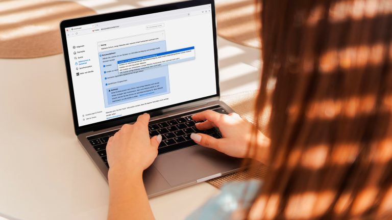 Eine Person sitzt vor einem MacBook und stellt Feinheiten bei der Cookie-Blockade von Firefox ein. Eine Person sitzt vor einem MacBook und stellt Feinheiten bei der Cookie-Blockade von Firefox ein.