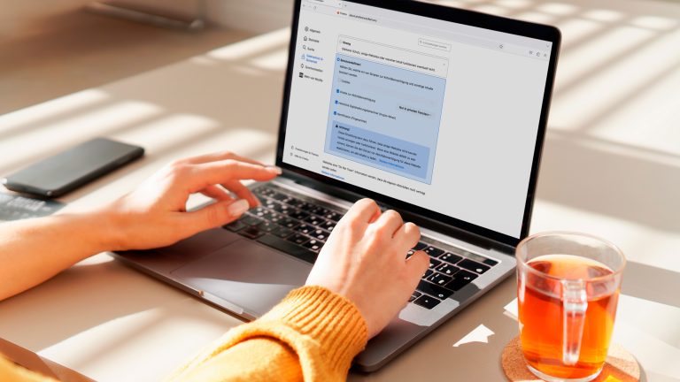 Eine Person sitzt vor einem MacBook und hat die Cookie-Einstellungen in Firefox aufgerufen.