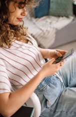 Eine Person sitzt auf einem Schreibtischstuhl und schaut auf ein Smartphone.