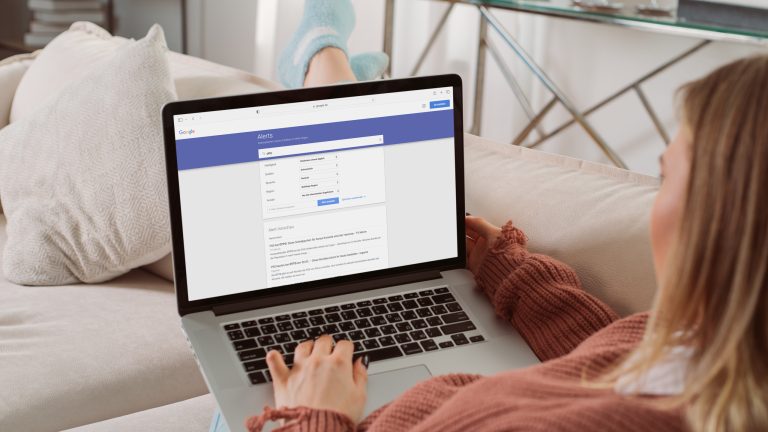Google Alerts einrichten, verwalten, löschen – ein Leitfaden Eine Person sitzt gemütlich auf einer Couch und schaut auf ihren Laptop. Hier ist der Startbildschirm von Google Alerts zu erkennen.
