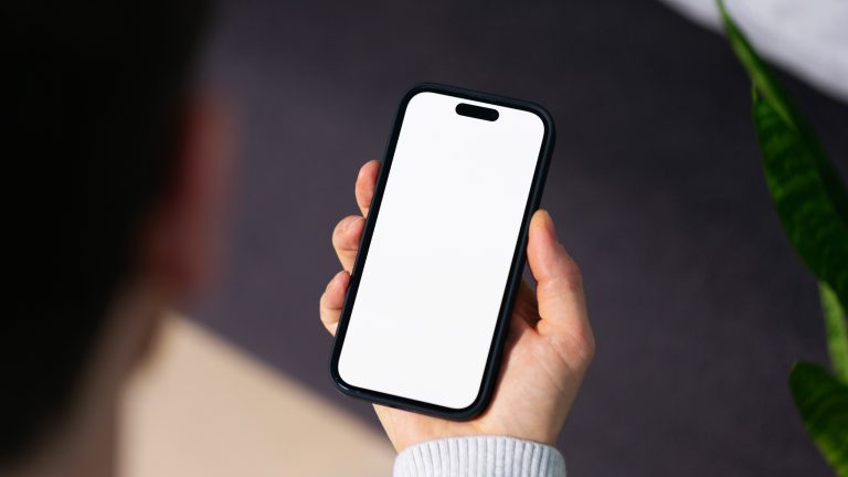 Eine Person hält ein iPhone mit weißem Display in der Hand.