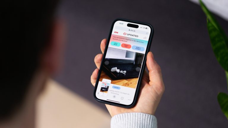 Eine Person hält ein iPhone in der Hand und macht einen Screenshot von UPDATED.