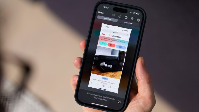Eine Person hält ein iPhone in der Hand, auf dem gerade ein Screenshot bearbeitet wird.