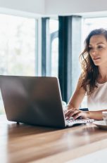 Eine Person sitzt vor einem Laptop, der auf einer Wohninsel steht.