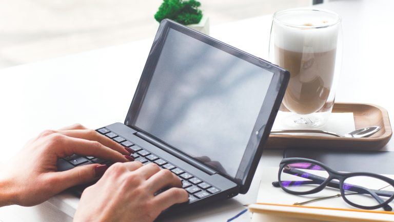 Eine Person sitzt vor einem Netbook und tippt auf dessen Tastatur. Eine Person sitzt vor einem Netbook und tippt auf dessen Tastatur.