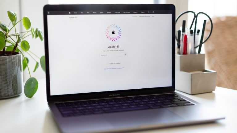 Ein MacBook mit geöffneter Apple-ID-Seite steht auf einem Schreibtisch.