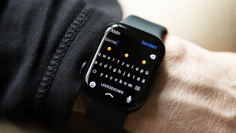 Nahaufnahme einer Apple Watch, auf der gerade die Tastatur zum Tippen einer Antwort auf eine WhatsApp-Nachricht zu sehen ist. Nahaufnahme einer Apple Watch, auf der gerade die Tastatur zum Tippen einer Antwort auf eine WhatsApp-Nachricht zu sehen ist.