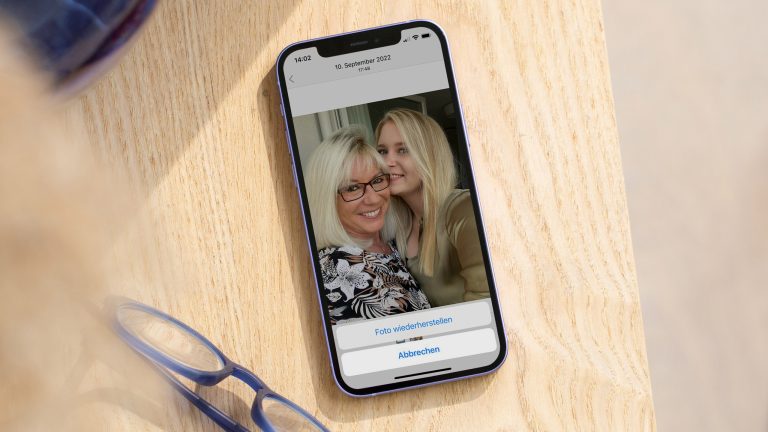 Ein Portrait von zwei Personen auf einem Android-Handy, auf dem die Option „Foto Wiederherstellen“ prangt.