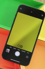 Ein iPhone mit geöffneter Kamera-App liegt auf bunten Schalen.