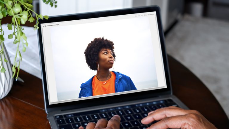 Auf einem Laptop ist das Bild einer Person zu sehen. Der Hintergrund ist Schwarz-Grau.