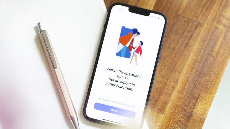 Auf einem iPhone ist die Einrichtung von Signal zu sehen. Daneben liegen ein Stift und ein Block. Auf einem iPhone ist die Einrichtung von Signal zu sehen. Daneben liegen ein Stift und ein Block.