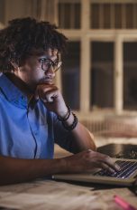 Eine Person sitzt am Schreibtisch vor einem Computer.