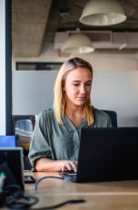 Eine Person sitzt in einem Büro vor einem Windows-Laptop.