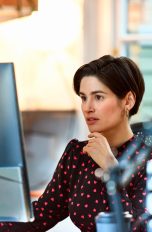 Eine Person sitzt in einem Büro vor einem Computer-Display.