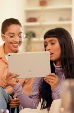 Zwei Personen sitzen auf einem Sofa und schauen gemeinsam auf ein Google Pixel Tablet.