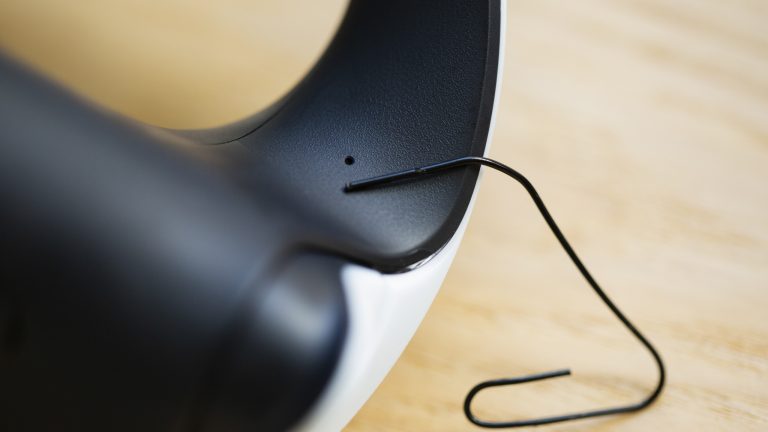 Nahaufnahme der Öffnung, in der sich die Reset-Taste beim Sense-Controller verbirgt. Nahaufnahme der Öffnung, in der sich die Reset-Taste beim Sense-Controller verbirgt.