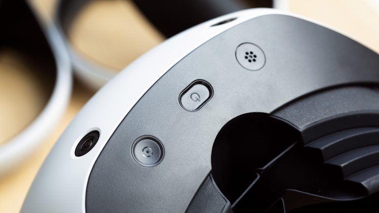Nahaufnahme der Unterseite einer PSVR 2. Zu sehen sind die Einschalt- und die Taste für den Passthrough-Modus. Nahaufnahme der Unterseite einer PSVR 2. Zu sehen sind die Einschalt- und die Taste für den Passthrough-Modus.