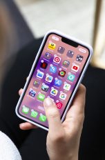 Eine Person hält ein iPhone in der Hand, auf dem gerade Apps gelöscht oder verschoben werden sollen.