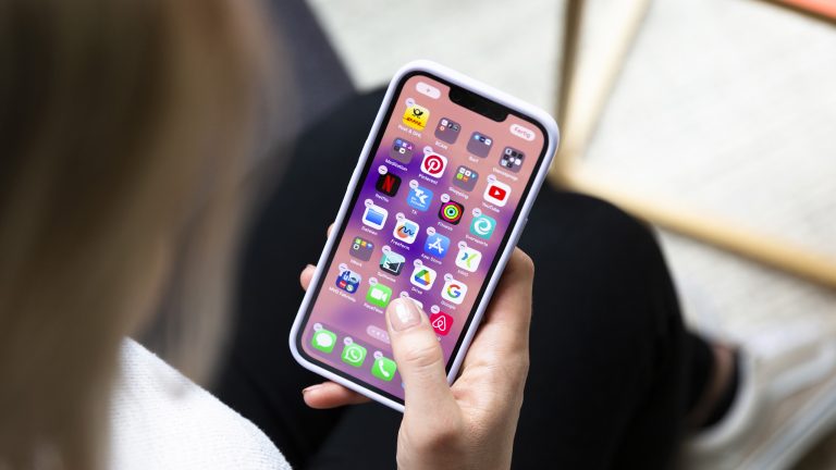 Eine Person hält ein iPhone in der Hand, auf dem gerade Apps gelöscht oder verschoben werden sollen.