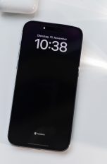 Ein iPhone 14 Pro Max liegt neben einem MacBook auf einem Schreibtisch.