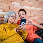 Zwei Personen sitzen auf einer Couch und schauen auf ein iPhone.