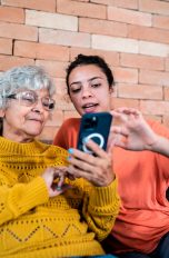 Zwei Personen sitzen auf einer Couch und schauen auf ein iPhone.