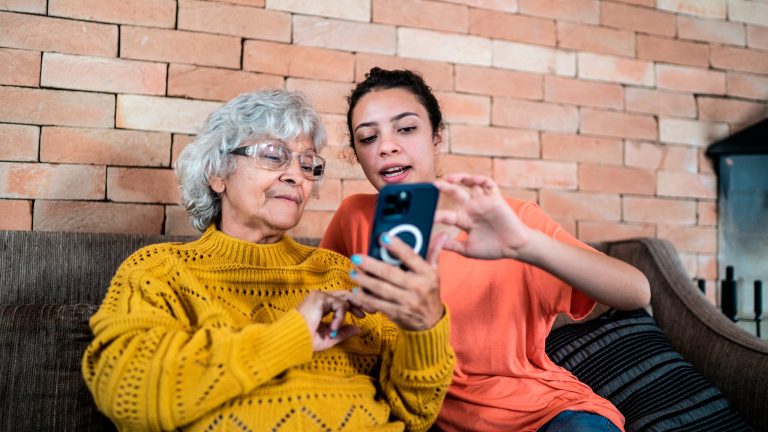 Zwei Personen sitzen auf einer Couch und schauen auf ein iPhone.