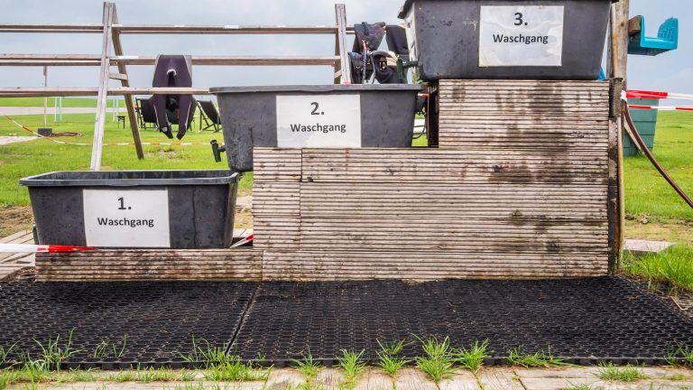 Drei Eimer zum Waschen von Neoprenanzügen stehen nebeneinander. Im Hintergrund sind einige Anzüge aufgehängt. Drei Eimer zum Waschen von Neoprenanzügen stehen nebeneinander. Im Hintergrund sind einige Anzüge aufgehängt.