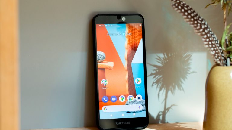 Ein Fairphone 4 steht auf einem Regal neben einer Pflanze.