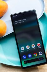 Ein Google Pixel 6a ist an Schalen angelehnt. Das Display ist an und zeigt den App-Drawer.