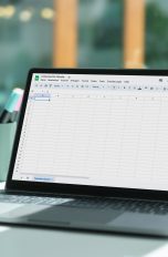 Ein MacBook steht auf einem Tisch. Darauf ist Google Tabellen zu sehen.