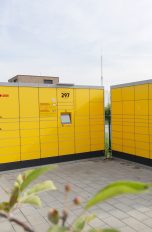 Gelbe Selbstbedienungs-Schließfächer von DHL auf Asphaltboden.