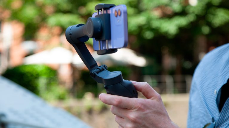 Eine Person hält einen Gimbal in der Hand, in dem ein iPhone 12 eingesetzt ist.