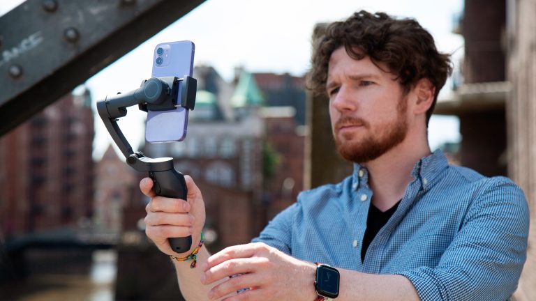 Eine Person hält einen Gimbal in der Hand, in der ein iPhone 12 hochkant eingesetzt ist.