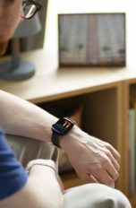 Eine Person sitzt an einem Tisch und schaut auf ihre Apple Watch.