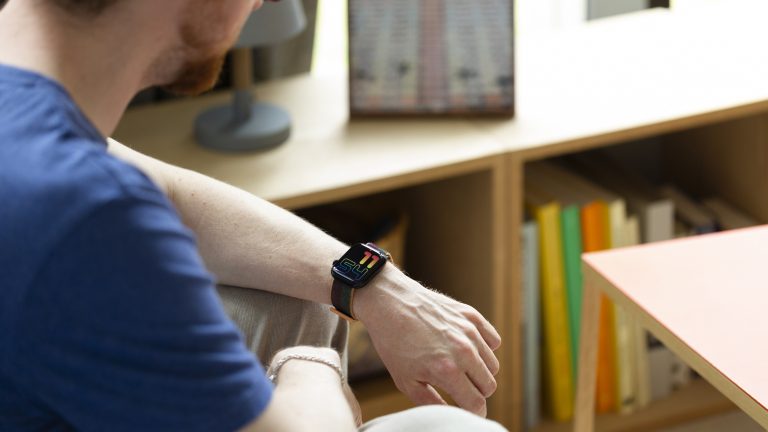 Eine Person sitzt an einem Tisch und schaut auf ihre Apple Watch.